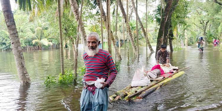 ঘরে হাঁটু পানি, ভেলায় বৃদ্ধাকে নিয়ে আশ্রয় খুঁজছেন